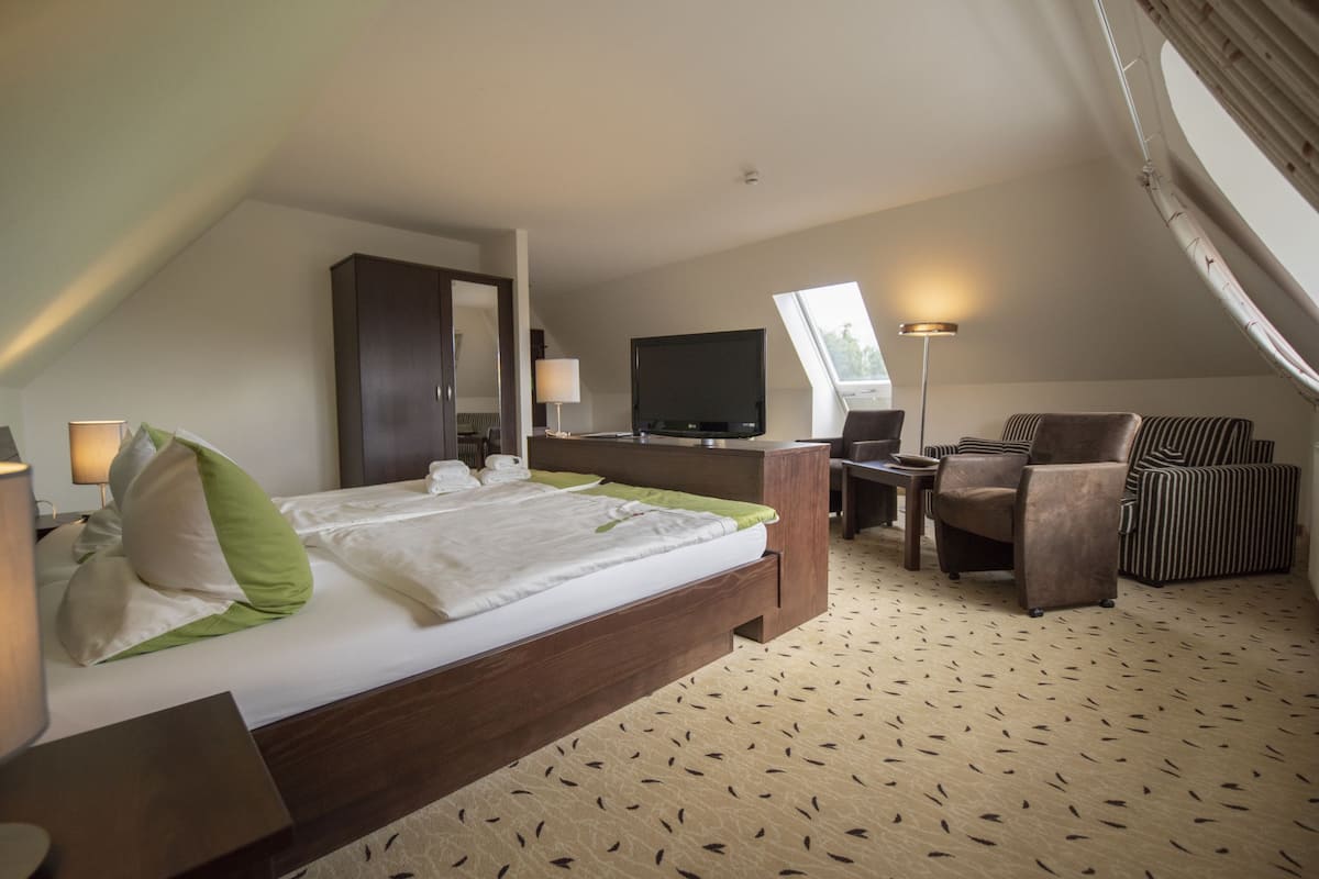 Une chambre d’hôtel avec un lit, un bureau, une chaise, une télévision et une lampe.