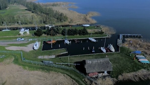 An aerial view of a marina with boats docked, a small building, and a grassy area.