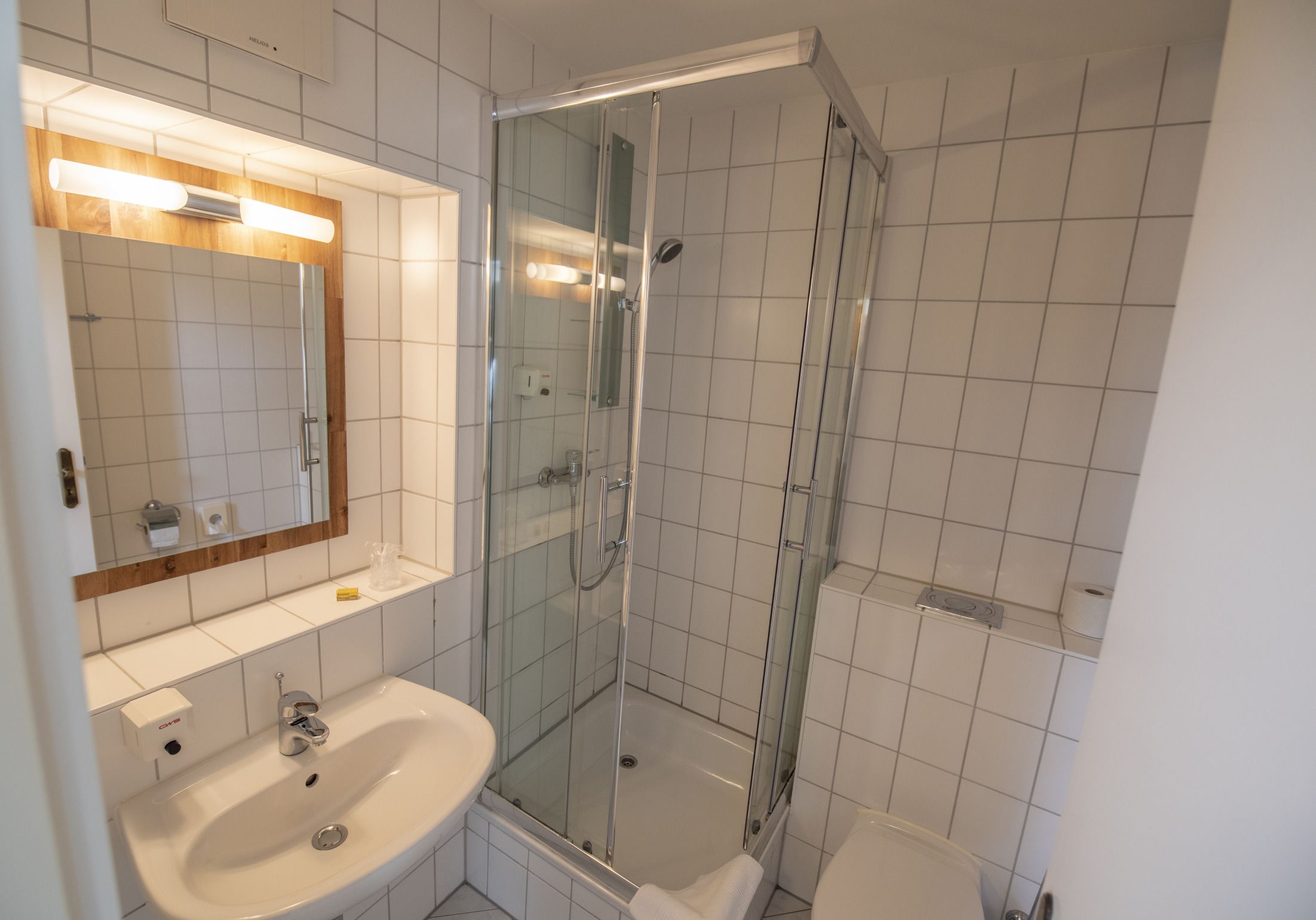 Une salle de bain moderne avec une douche en verre, un lavabo blanc et un miroir au-dessus du lavabo.