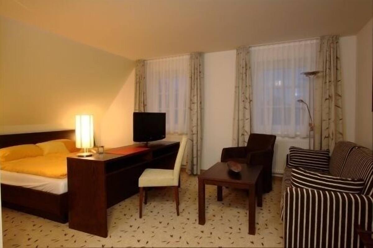 Une chambre d’hôtel comprenant un lit, un bureau avec une télévision, une chaise, un canapé et une lampe.