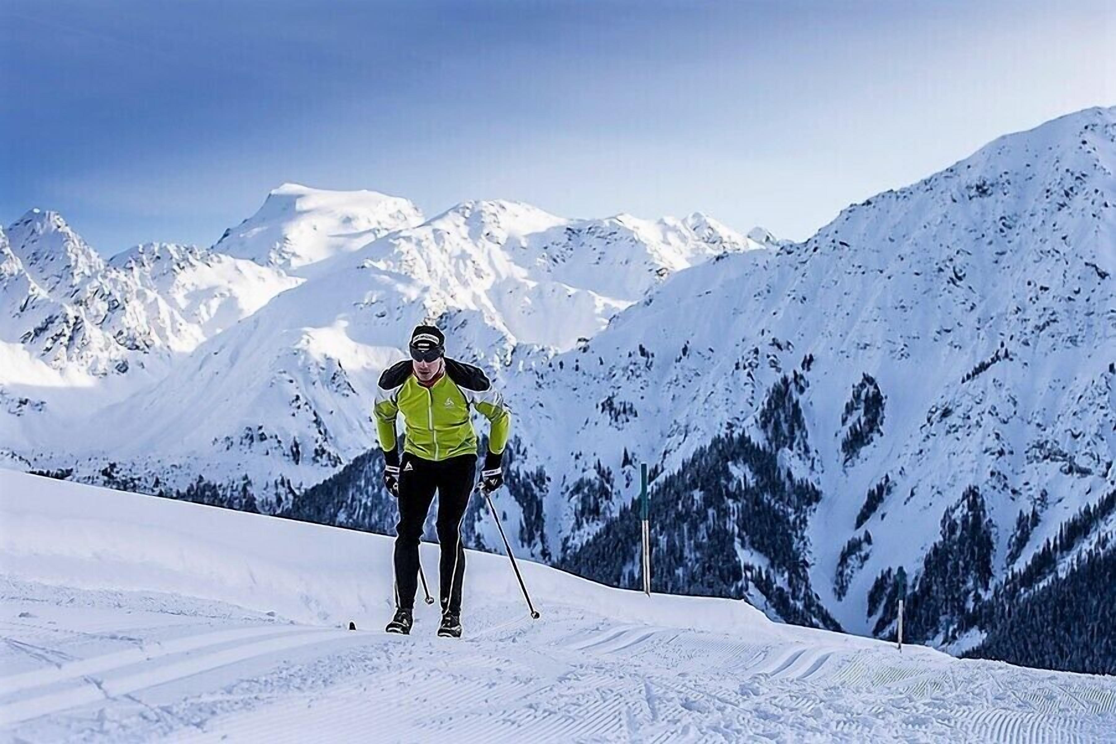 Una persona esquiando en una pendiente nevada, con montañas al fondo.