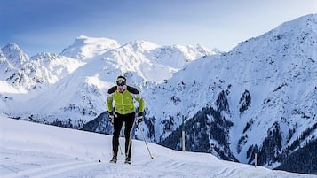 Una persona esquiando en una pendiente nevada, con montañas al fondo.