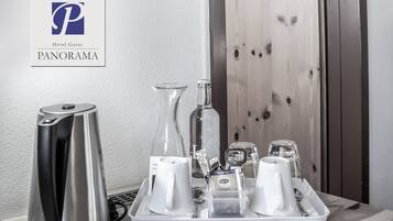 A hotel room with a tray of amenities including a kettle, a vase, and a tray with cups and a bottle of Lipton tea.