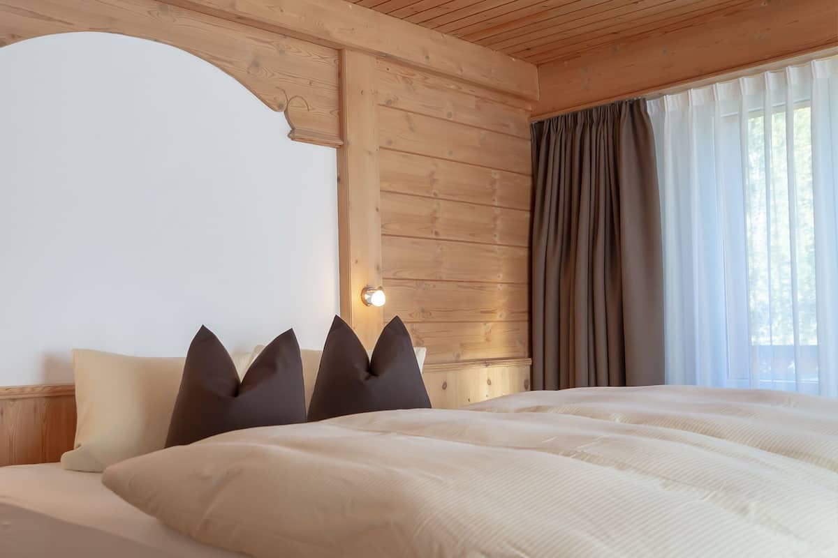 Un dormitorio con una cama grande, cabecera de madera y una ventana con cortinas.
