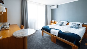 Habitación de hotel con cama, una mesa redonda, escritorio, silla, televisión y aire acondicionado.