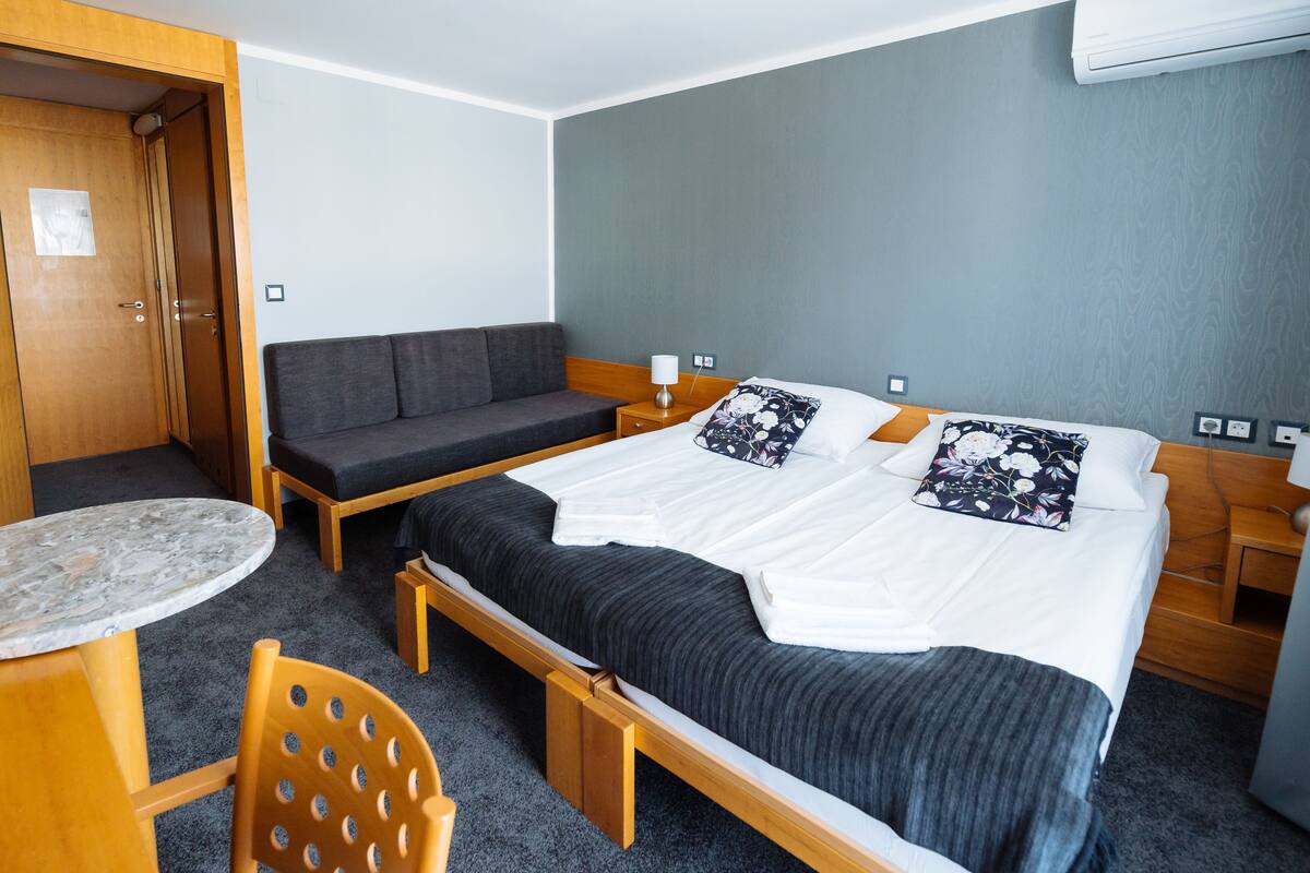 Una habitación de hotel con cama, sofá, una mesita y una silla.