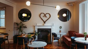 Un espace de restauration chaleureux avec une cheminée, des tables rondes et des sièges confortables.