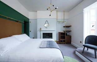 Un dormitorio con una cama grande, una chimenea, una estantería de madera y una silla.