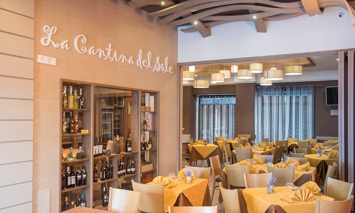 Un restaurante con bodega de vinos y varias mesas dispuestas.