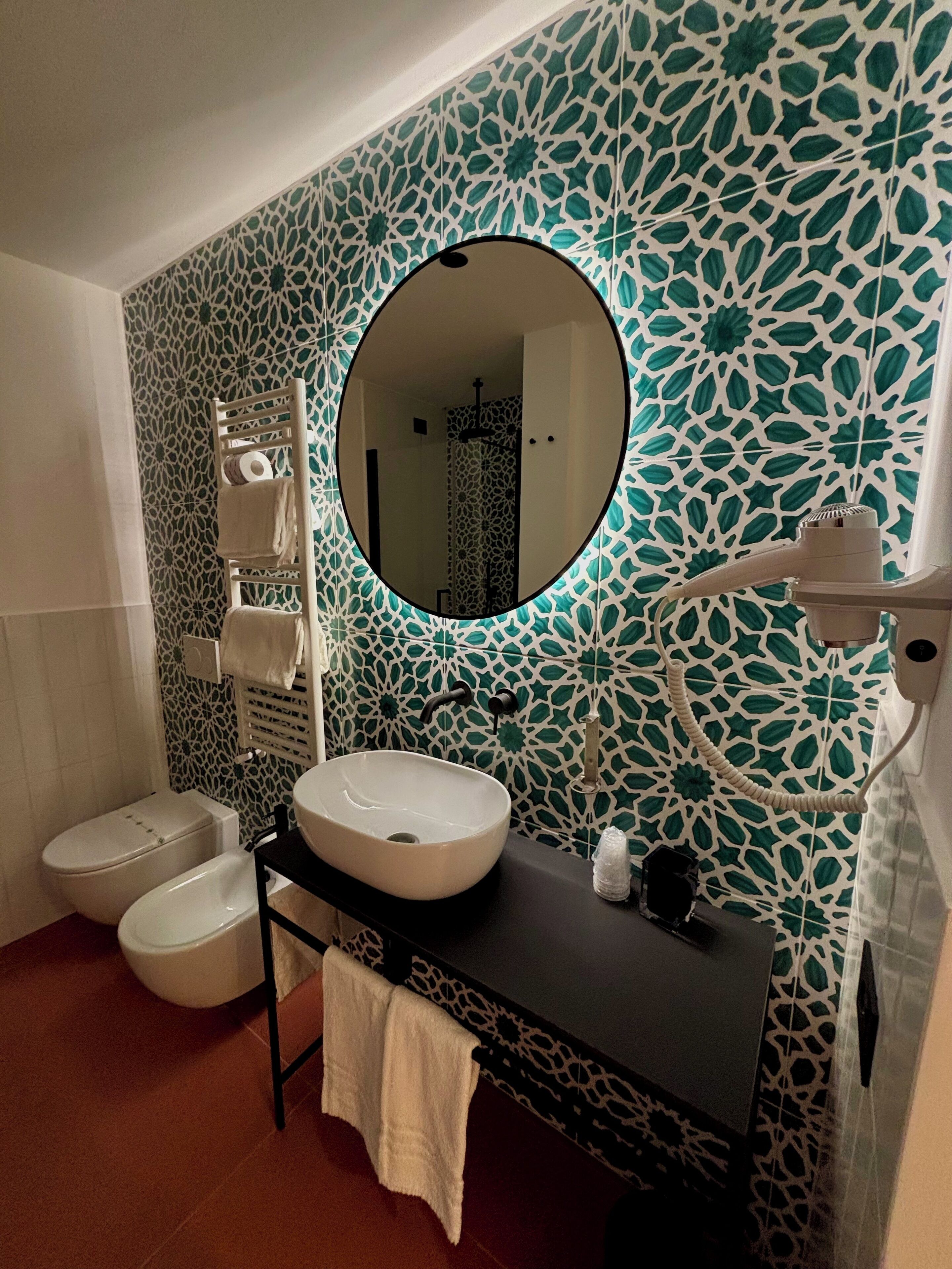 A bathroom with a white sink, two toilets, a towel rack, and a mirror.