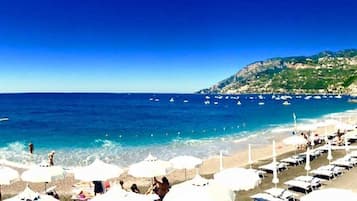 On the beach, black sand, sun-loungers, beach umbrellas