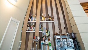 A modern bar area with wooden slats on the ceiling and shelves stocked with bottles. - Hotel Sole (Maiori)