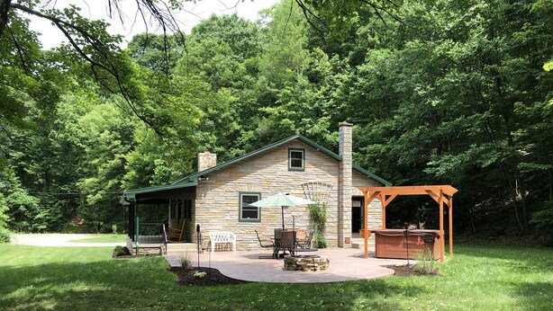 Une maison en pierre dotée d’un patio, d’un espace salon extérieur et d’une pergola.
