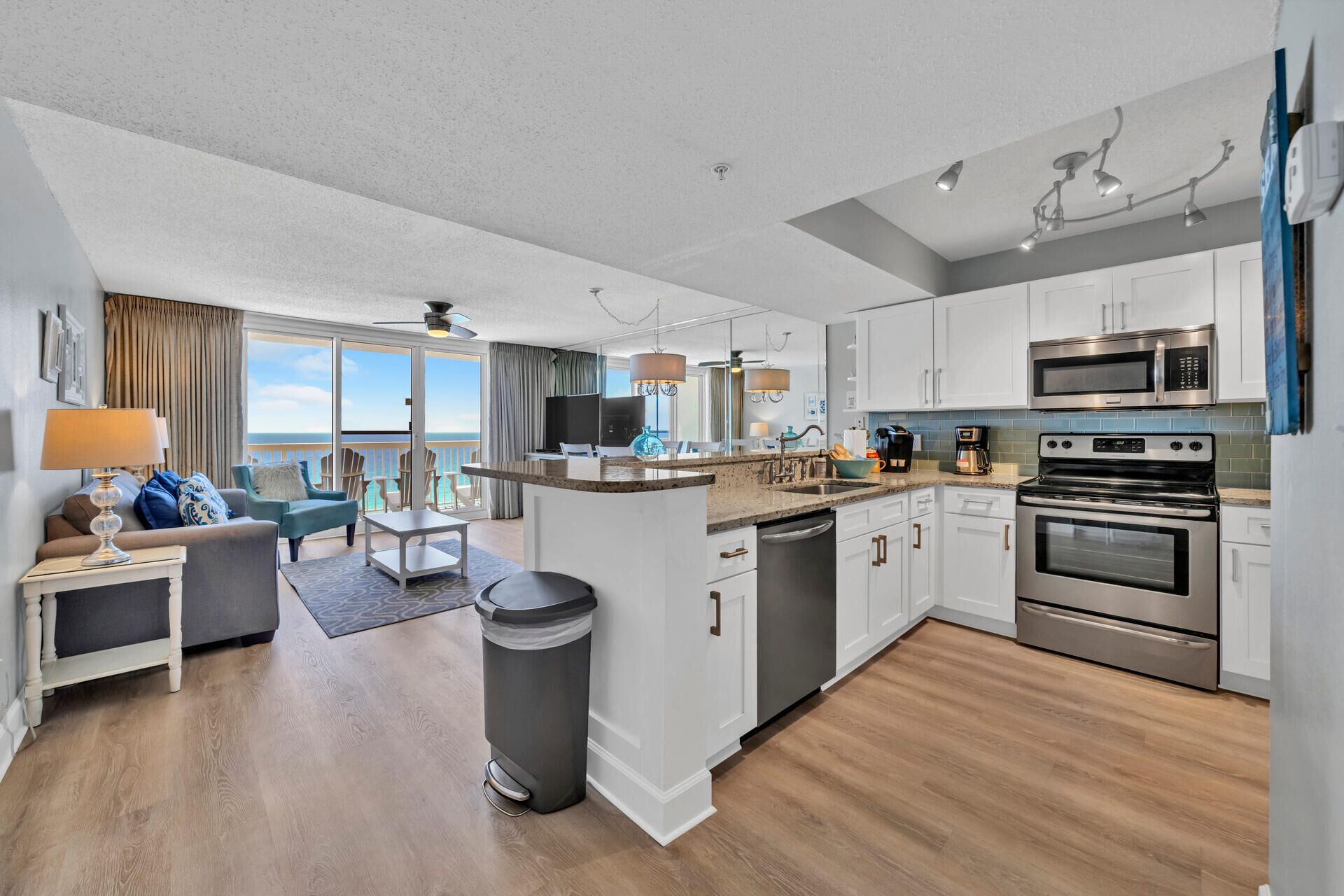 A modern kitchen with white cabinets, stainless steel appliances, and a view to the outside.