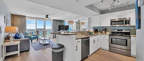 A modern kitchen with white cabinets, stainless steel appliances, and a view to the outside.