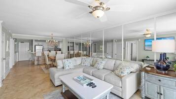 A spacious living room with a large sectional sofa, a coffee table, and a dining area in the background.
