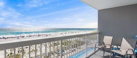 A balcony with a view of the beach and pool.