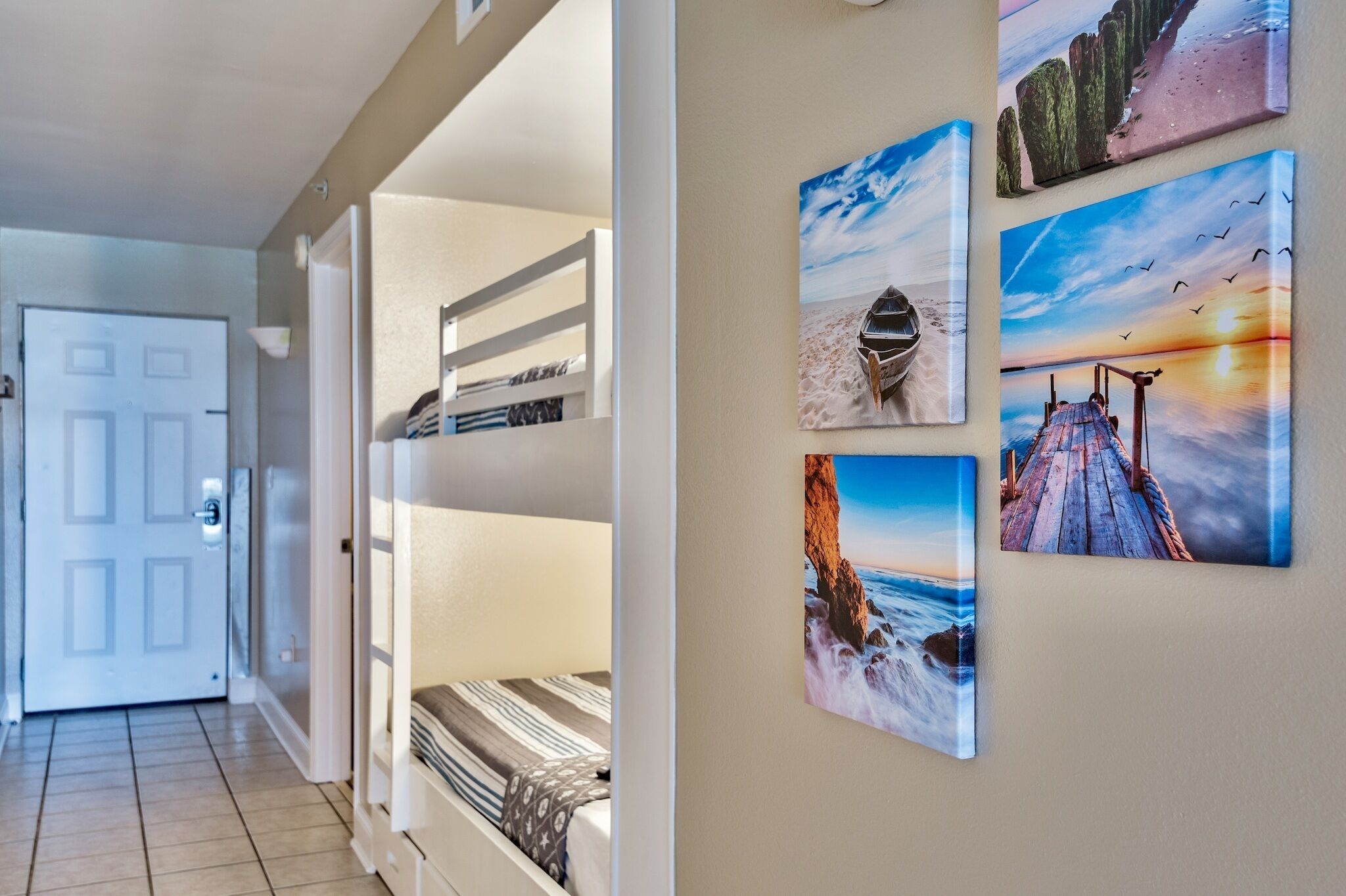 Een hal met een stapelbed, een deur en vier ingelijste foto's aan de muur.