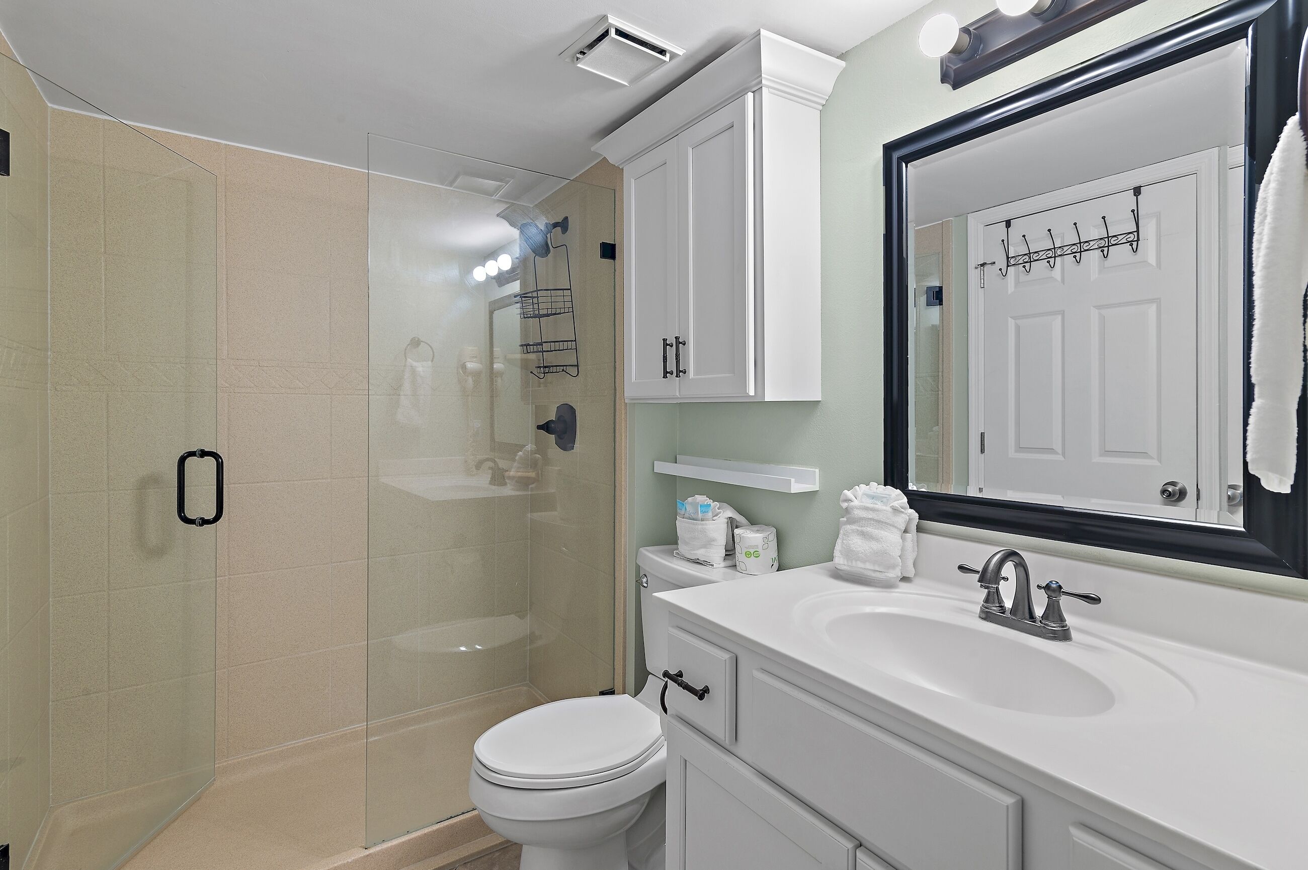 A modern bathroom with a glass shower enclosure, a white toilet, a sink with a mirror, and a towel rack.