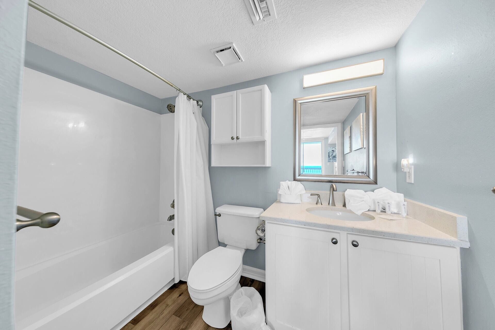 A bathroom with a shower, toilet, sink, and cabinet.