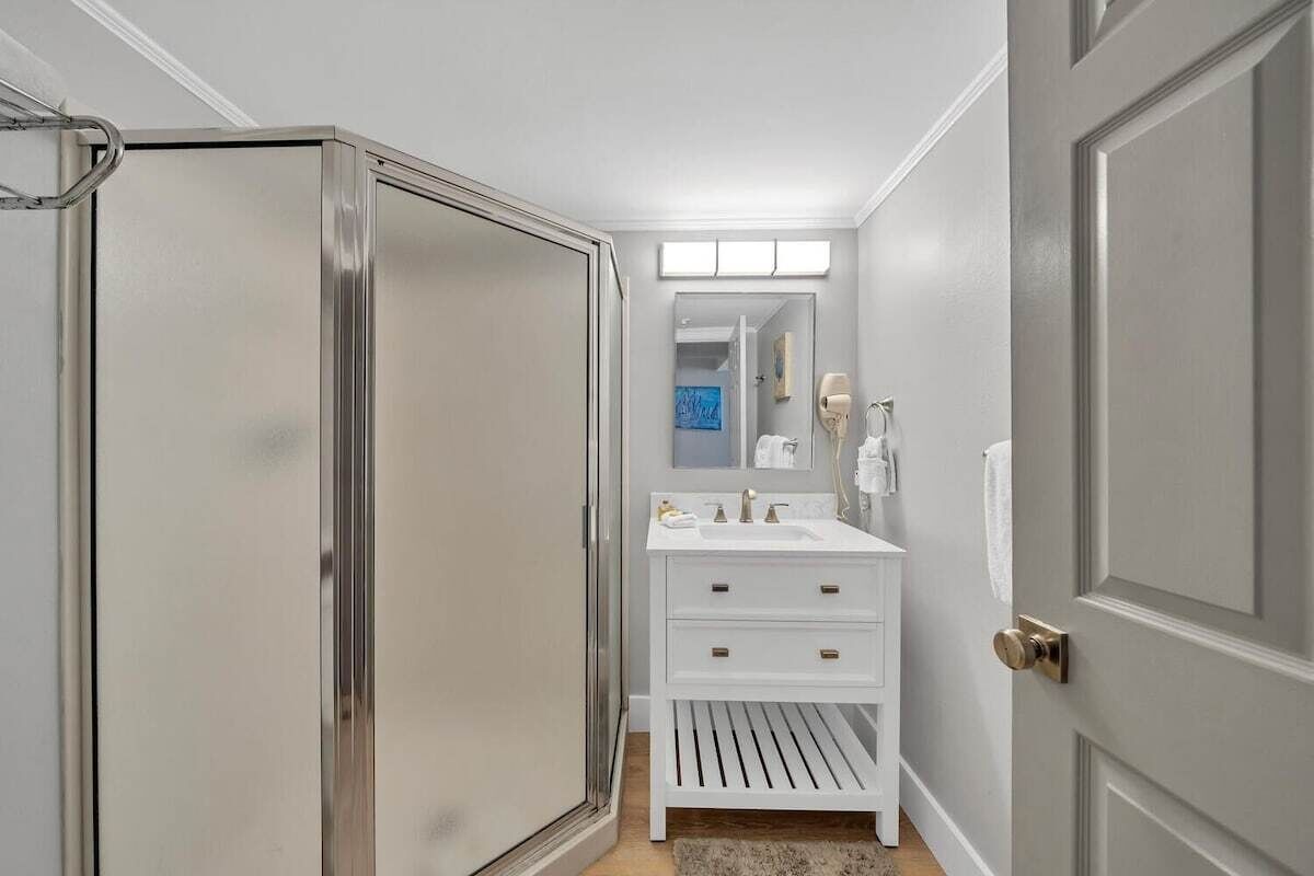 Un baño con tocador blanco, un espejo y cabina de ducha.