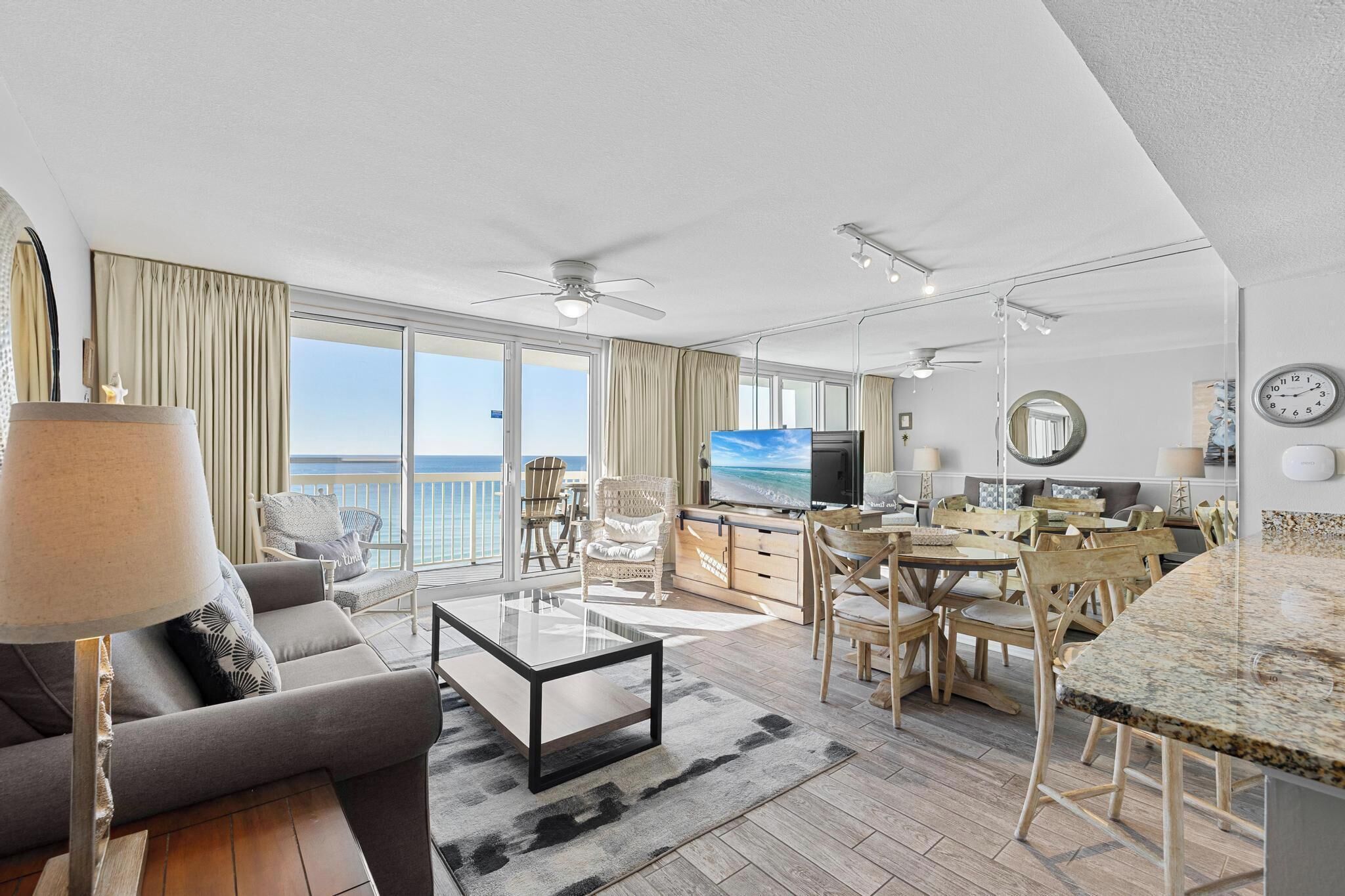 Un vaste salon doté d’une grande télévision, de sièges confortables, d’un coin repas et d’un balcon offrant une vue sur la mer.