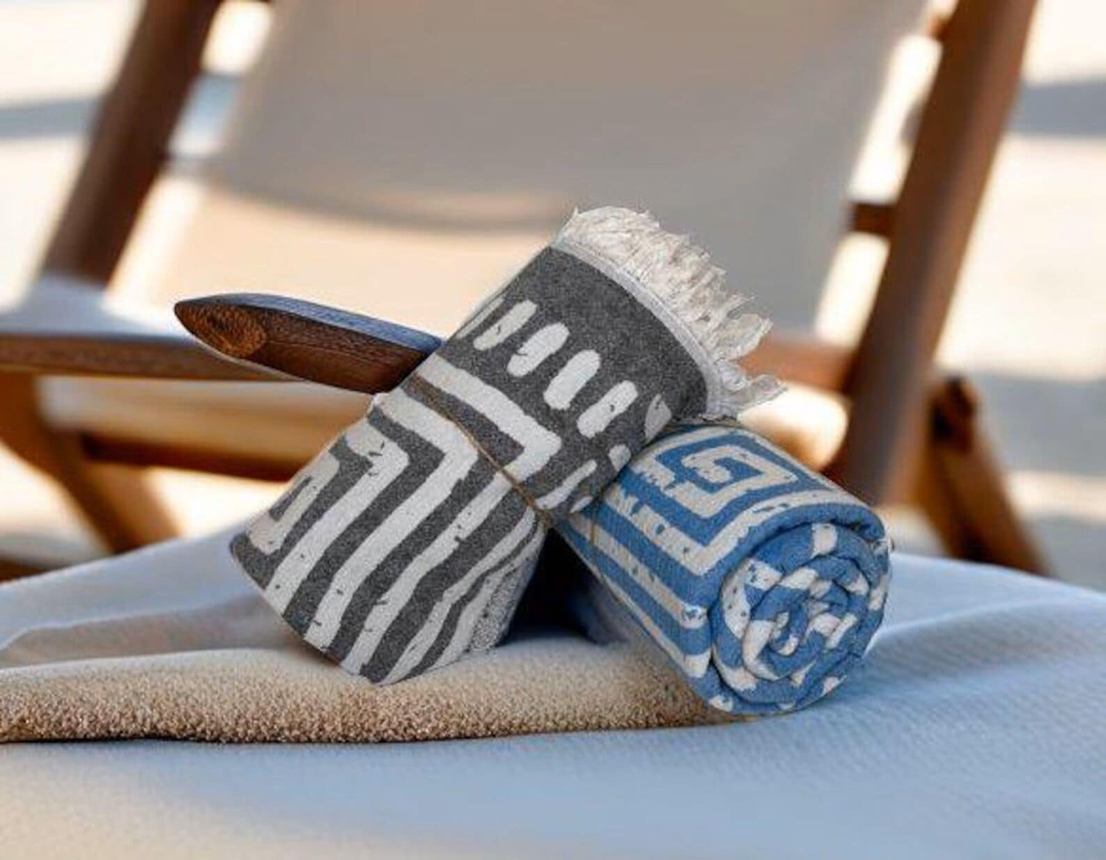 Une serviette pliée à motifs et une cuillère en bois posées sur un coussin beige.