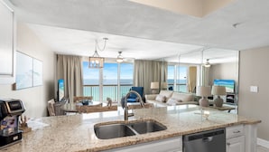 A spacious living area with a kitchen, a dining table, and a view of the ocean. - Pelican Beach Resort by Colasan (Destin)