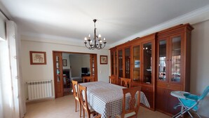 Ein Essbereich mit einem Tisch für vier Personen, Holzsesseln, einer Chandelüster und einem Schrank mit Glastüren.