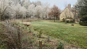 Un paisaje rural con una casa, un campo cubierto de hierba y árboles.
