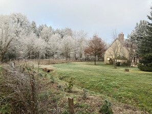 A rural landscape with a house, a grassy field, and trees.