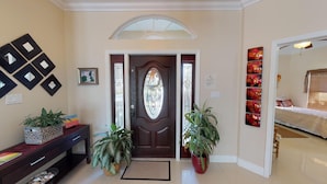 A well-lit entryway with a dark wooden door, a small desk with a plant, and a potted plant beside the door. - Savhaven - 4 Bed, 4 Bath with Pool, Sleeps 8 (2 minutes away from Spotts Beach) (Savannah)