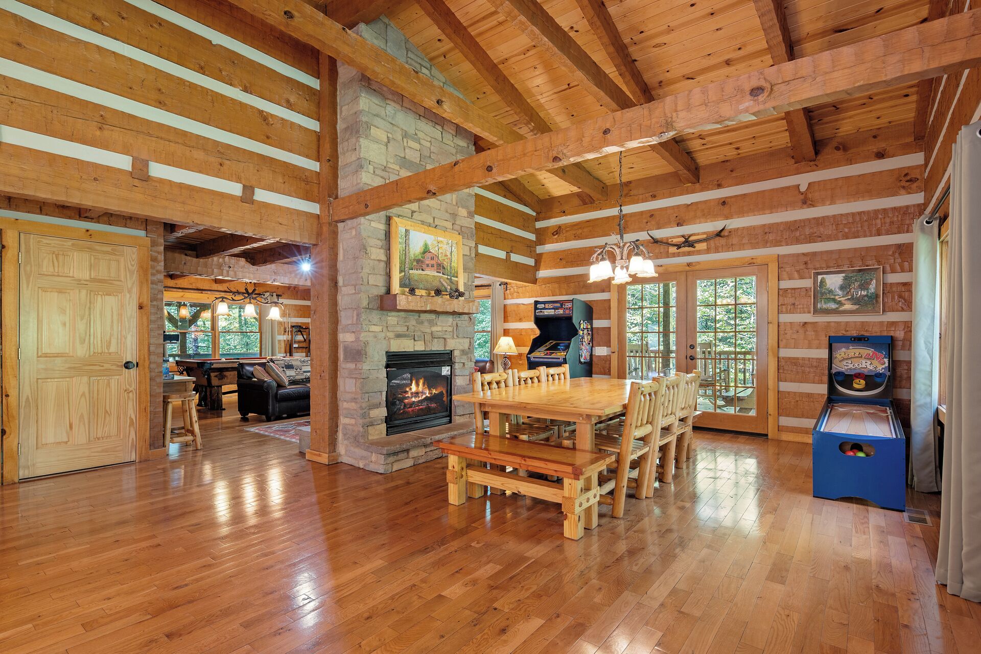 A spacious wooden interior with a fireplace, dining area, and arcade games.