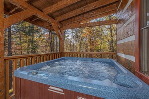A wooden deck with a hot tub, surrounded by trees with autumn foliage. - Appalachian Escape - Secluded Log Cabin Retreat with Hot Tub, Fire Pit & Games (Sevierville)