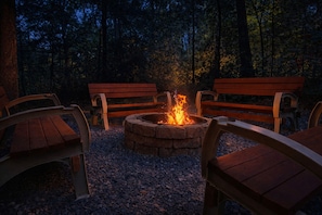 A fire pit surrounded by wooden benches in a forest setting.