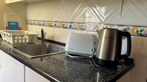 Een keuken met een spoelbak, een broodrooster en een koffiezetapparaat op het aanrecht.