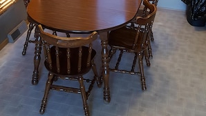 A dining room with a round wooden table surrounded by six wooden chairs.