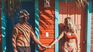 Una coberta de fusta amb una persona en banyador agafant la mà d'una altra persona en banyador.