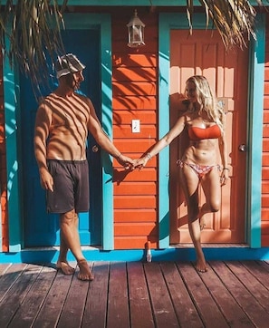 Una terraza de madera con una persona en traje de baño tomándose de las manos con otra persona en traje de baño.