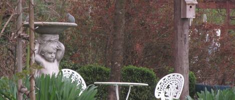 Un jardin avec une nichoir blanc, une table blanche et deux chaises blanches.