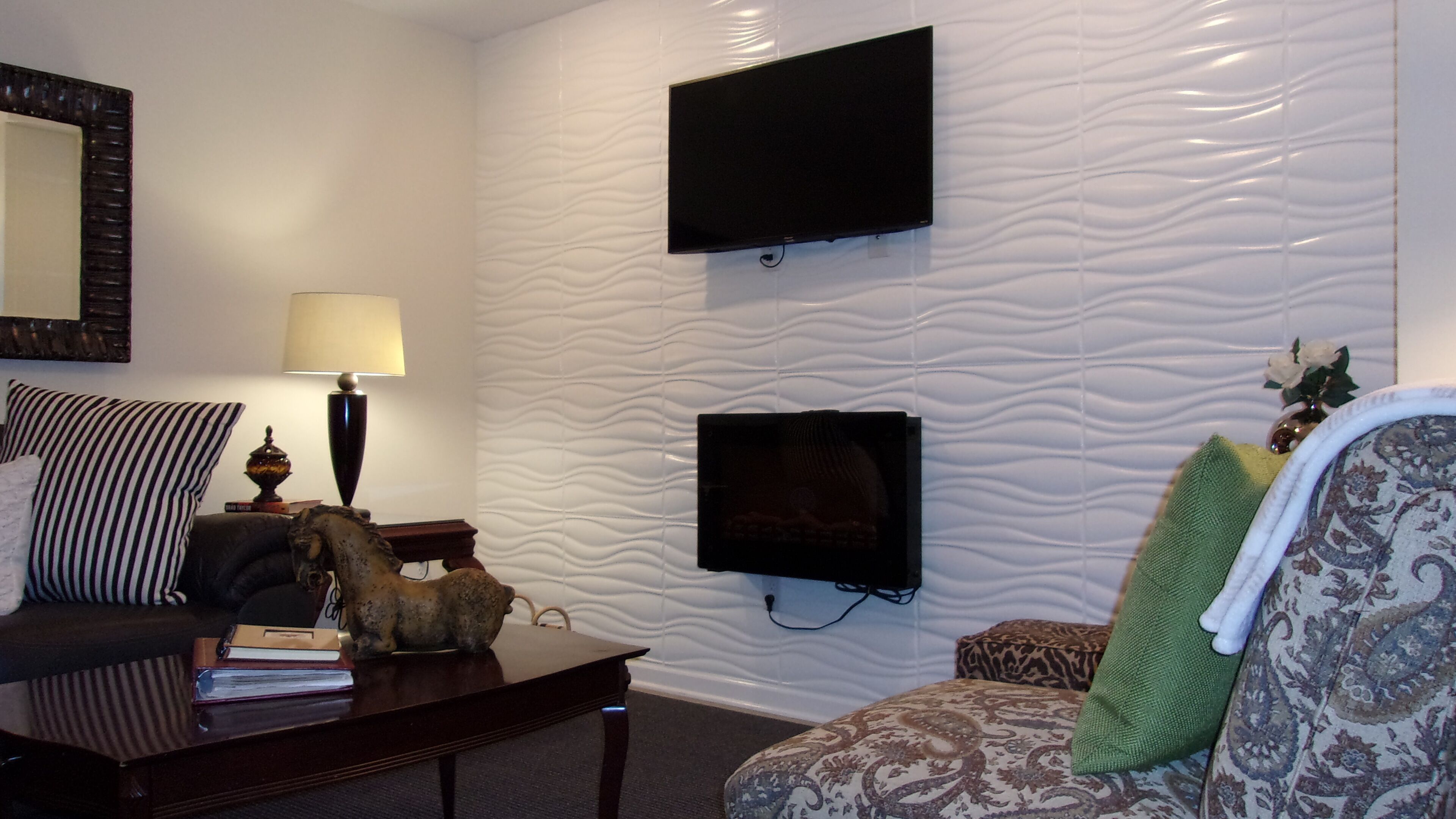 Een woonkamer met een bank, een salontafel, een lamp, een aan de muur bevestigde televisie en een decoratief paardje.