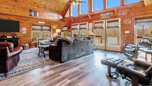 A spacious living room with a high ceiling, wooden walls, and large windows. -  7 person new HOT TUB  at Stunning Log Cabin 4 bed 4 full bath  5 min  to TI (Rutherfordton)