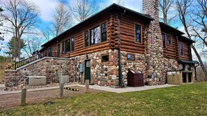Eine Blockhütte mit Steinfassade, einer grünen Tür und einer Treppe zum Eingang.