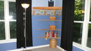A room with a blue wall, a bookshelf, a lamp, and a window.