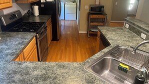 A kitchen with granite countertops, stainless steel appliances, wooden cabinets, and a built-in dishwasher. - Nestled Among Majestic Trees, Hilltop Hideaway is a Woodland Sanctuary (Amissville)