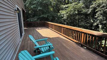 Una terraza de madera con barandilla, rodeada de árboles.