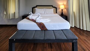 Een hotelkamer met een groot bed, twee nachtkastjes, een lamp en gordijnen.