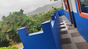 A blue and white building with a checkered floor and a view of lush greenery and mountains in the background. - Hostal Alcazaba (Puerto Lopez)