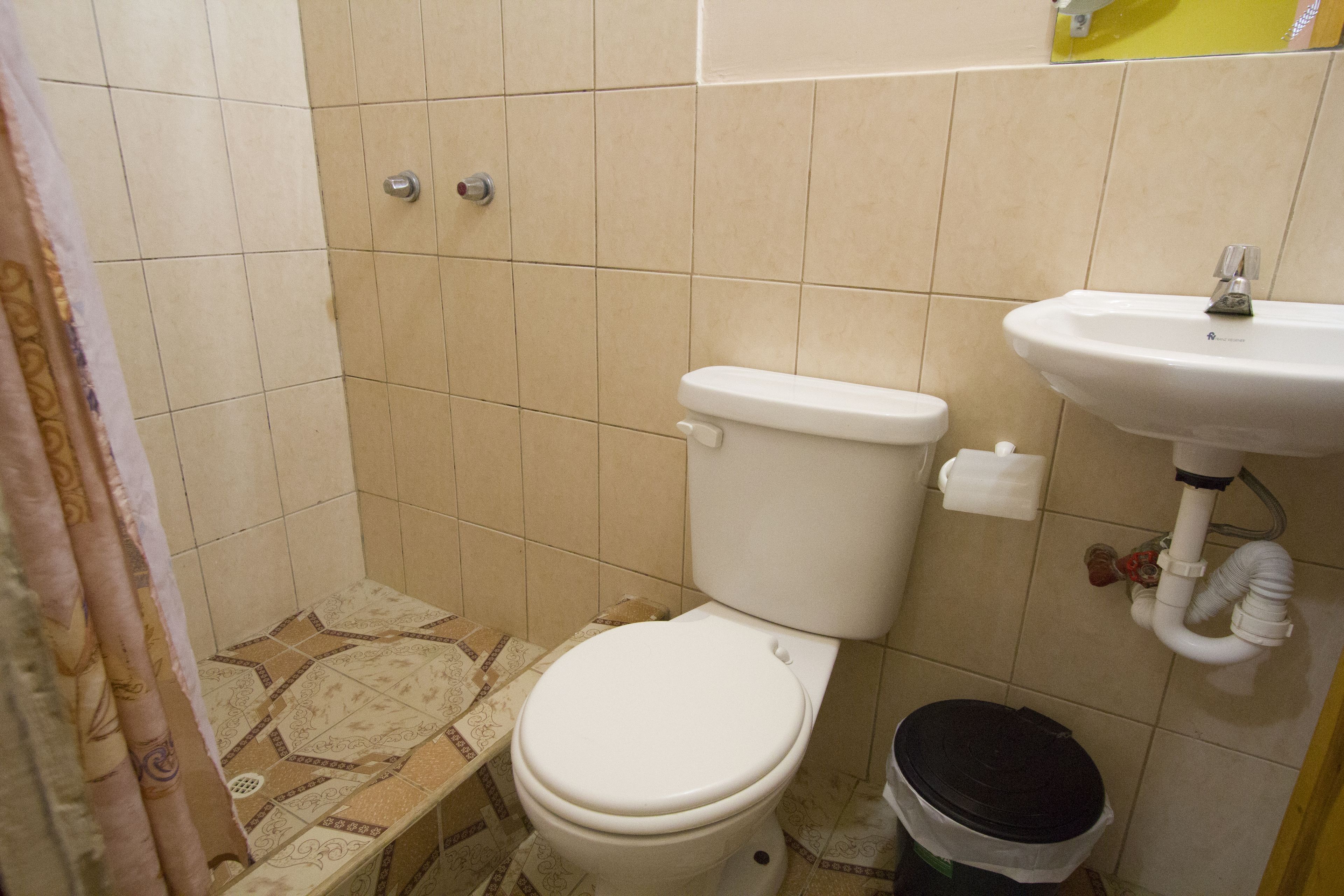 Une petite salle de bain avec des toilettes, un lavabo et une poubelle.