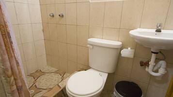 Une petite salle de bain avec des toilettes, un lavabo et une poubelle.